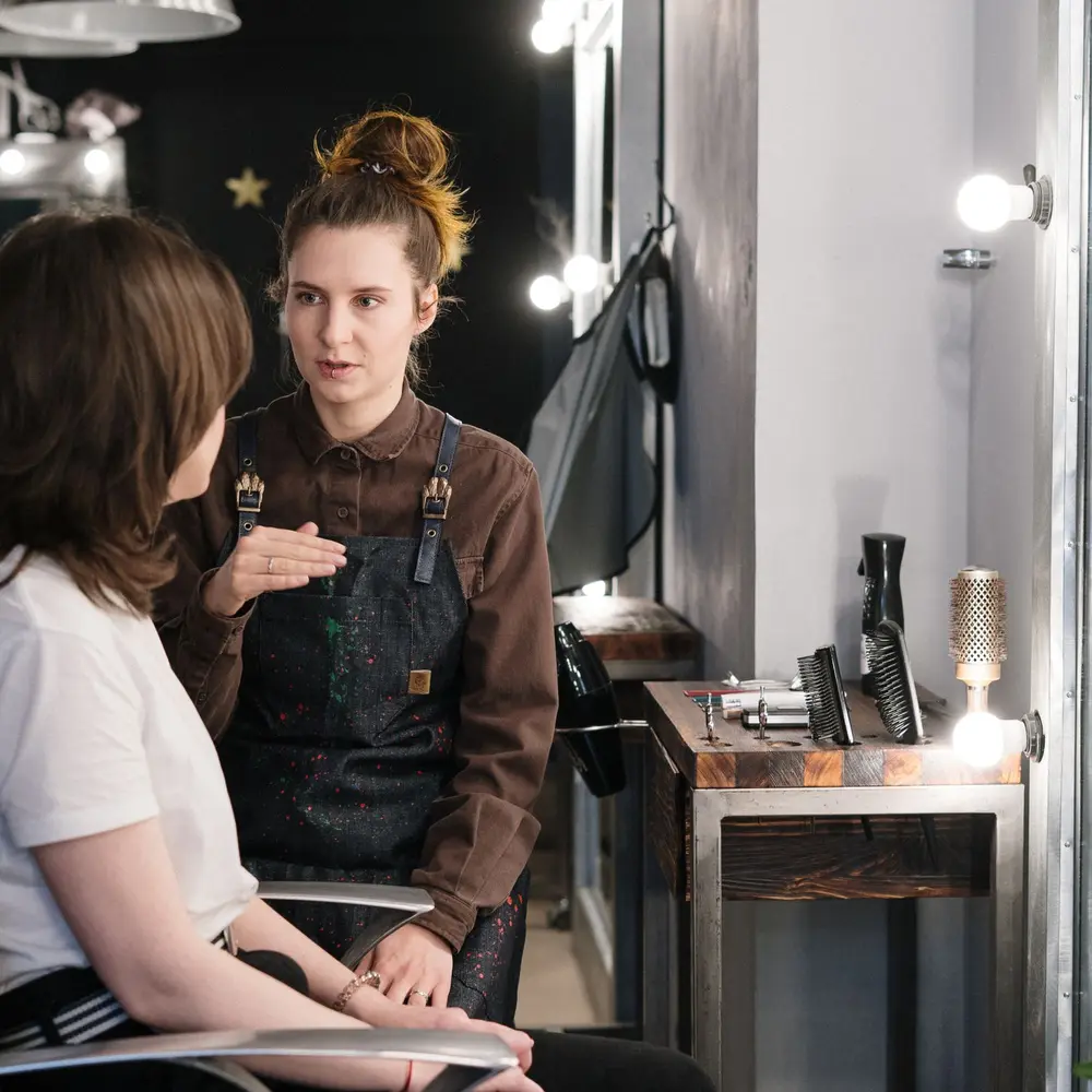 Hairstylist talking through a cut with a client at her station